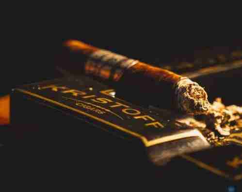 Premium Kristoff cigar with ash resting on a branded Kristoff Cigars ashtray.