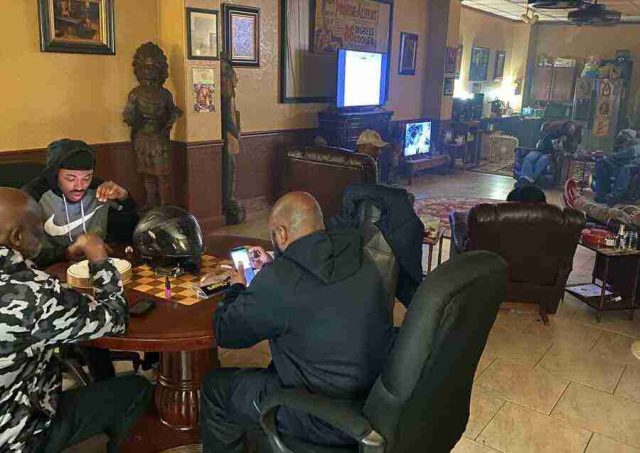 membership-lounge - 13 A group of patrons relaxing, talking, and smoking cigars in comfortable leather chairs inside the dimly lit lounge at F&M Cigars.