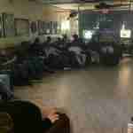 A group of patrons relaxing, talking, and smoking cigars in comfortable leather chairs inside the dimly lit lounge at F&M Cigars.