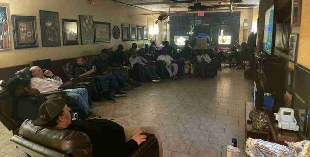 membership-lounge - 2 A group of patrons relaxing, talking, and smoking cigars in comfortable leather chairs inside the dimly lit lounge at F&M Cigars.