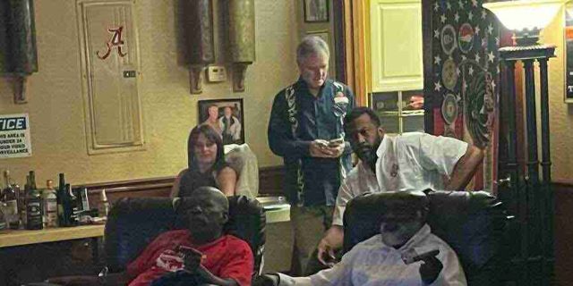 membership-lounge - 6 A group of patrons relaxing, talking, and smoking cigars in comfortable leather chairs inside the dimly lit lounge at F&M Cigars.