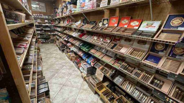 walk-in-humidor - 2 Inside the walk-in humidor at F&M Cigars, featuring fully stocked wooden shelves displaying an extensive selection of premium boutique and classic cigar brands.