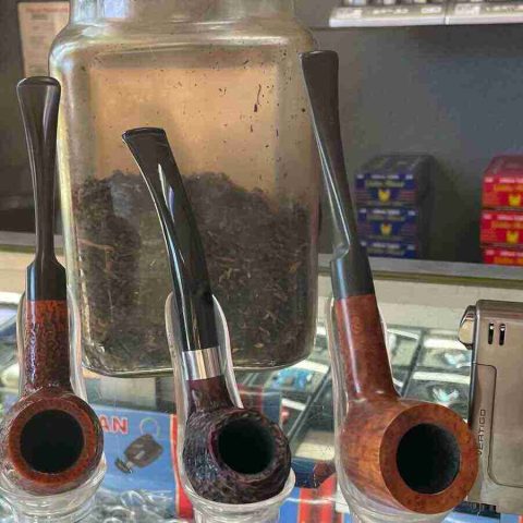 walk-in-humidor - 3 Three premium briar pipes displayed in front of a display of pipe tobacco