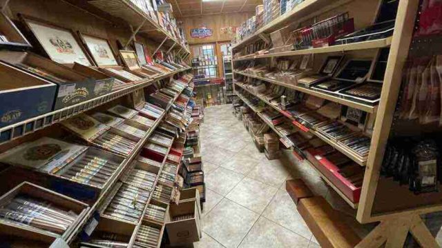 walk-in-humidor - 9 Inside the walk-in humidor at F&M Cigars, featuring fully stocked wooden shelves displaying an extensive selection of premium boutique and classic cigar brands.